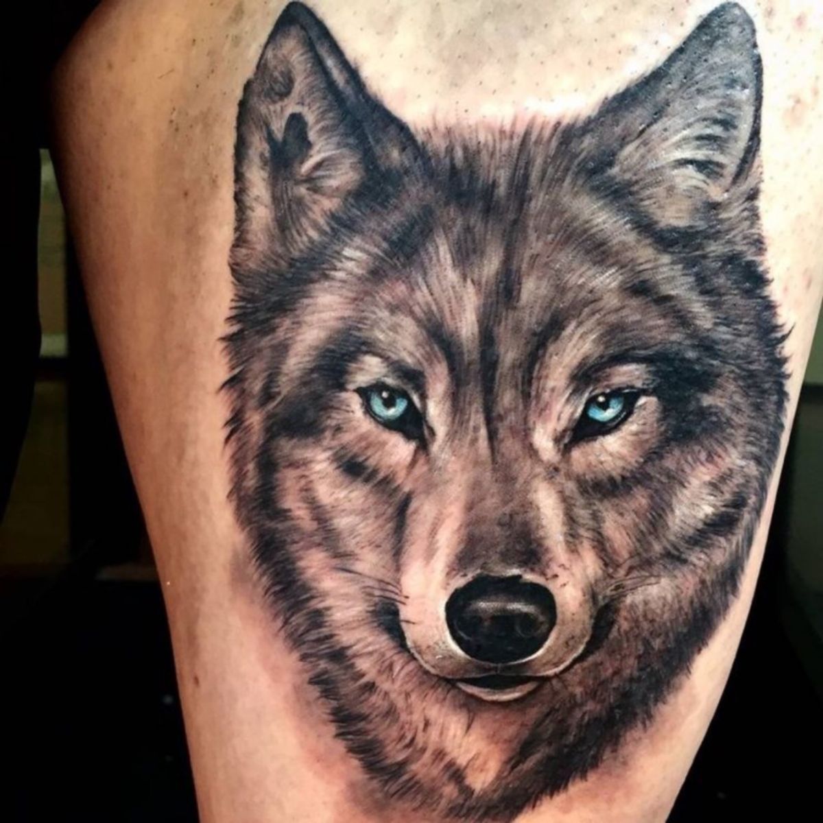 A Wolf With Blue Eyes Is Shown In This Tattoo Design